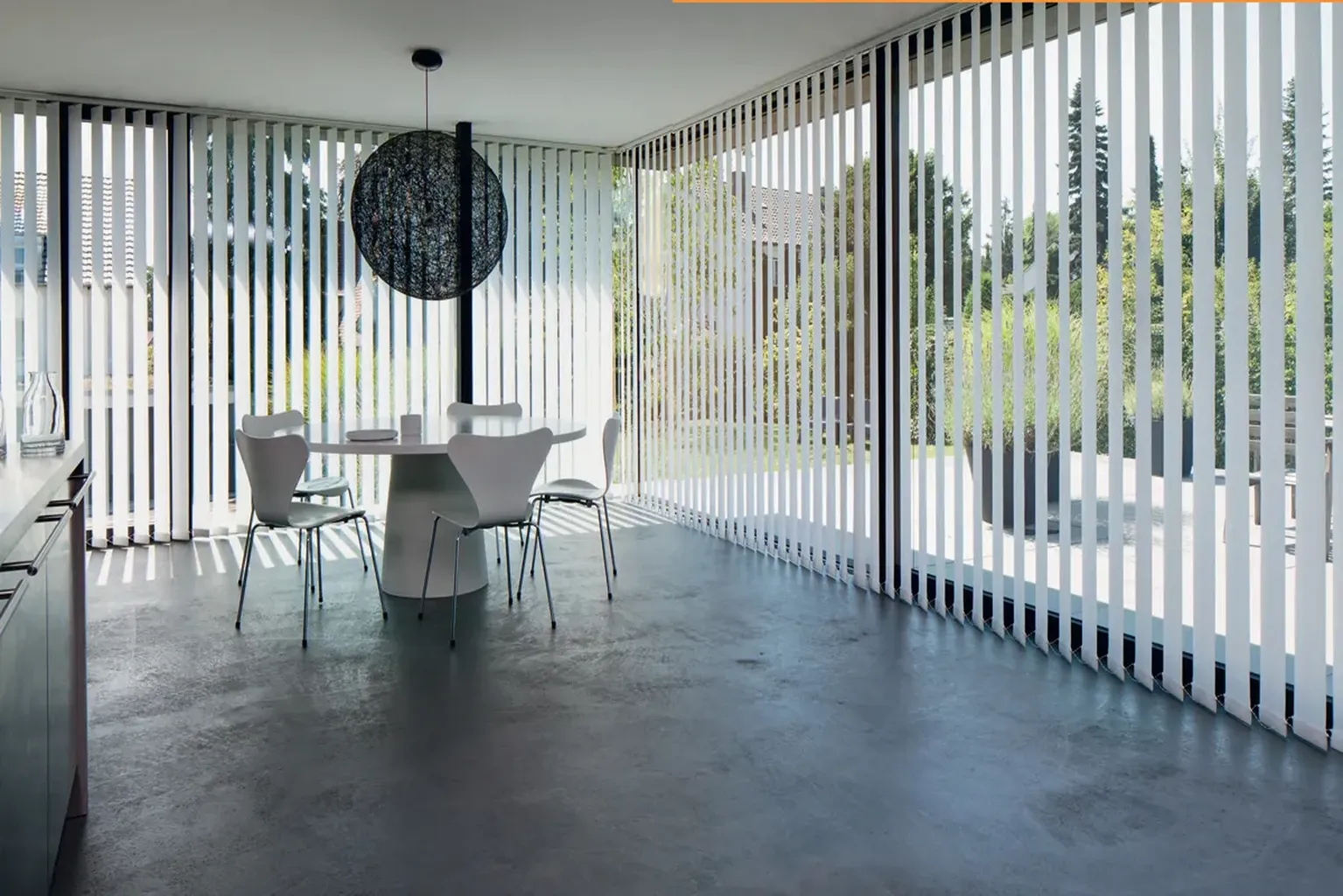 Cortina vertical traslúcida decorativa en salón con vistas al exterior